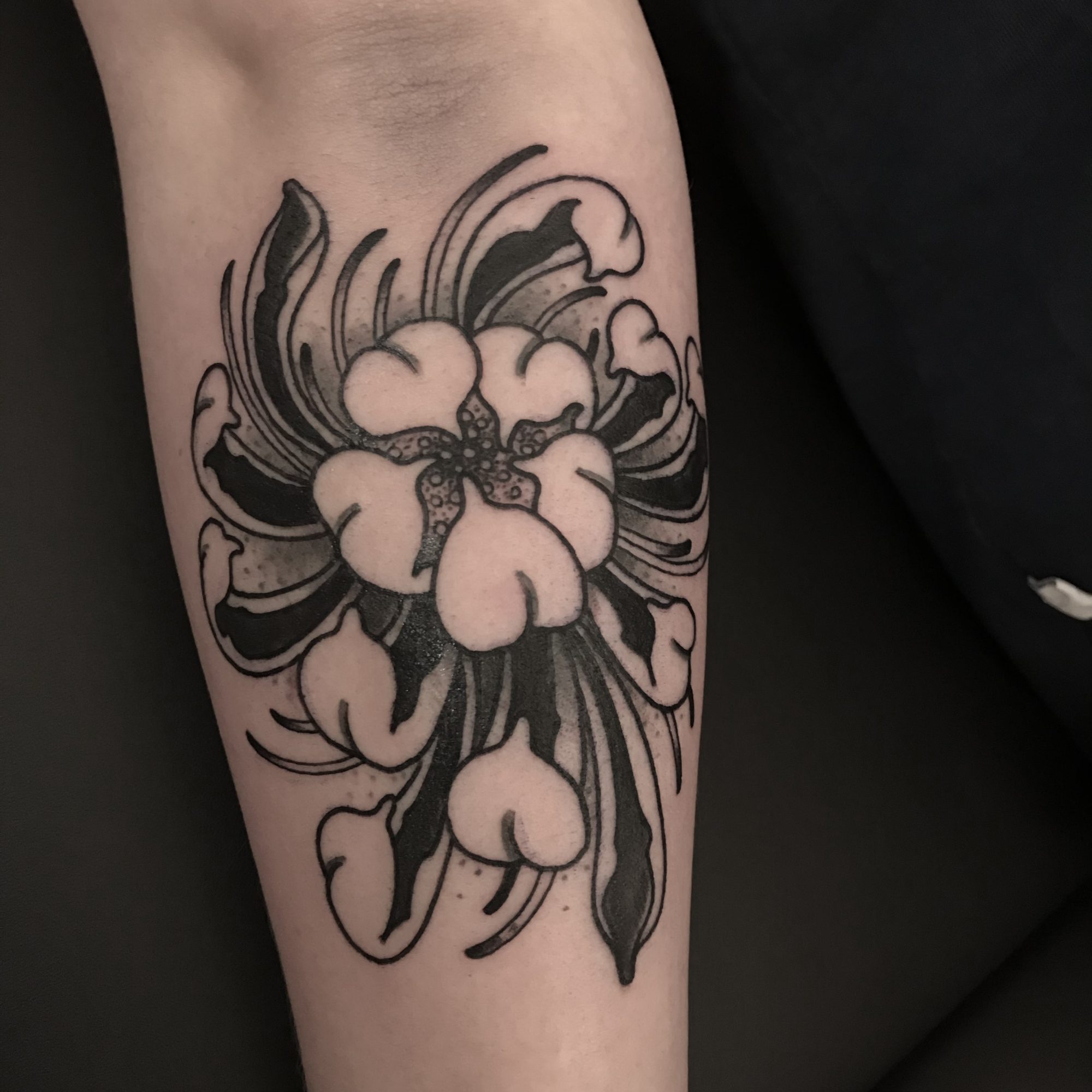 Große Blüte mit schwarzen Blättern am Unterarm, Blumen Tattoo von Andre bei Eine Liebe Tätowiergeschäft in Bochum