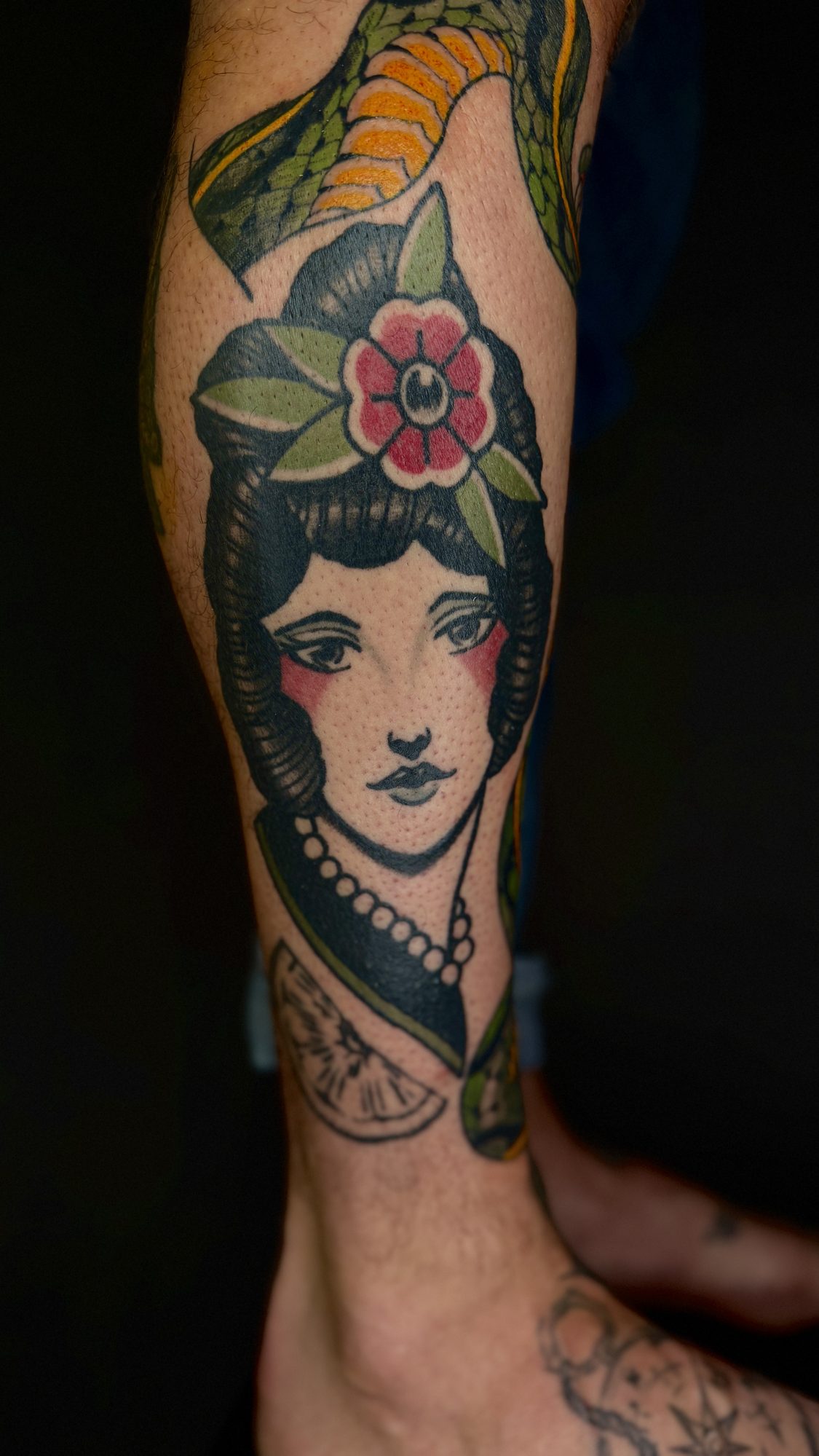 Frauenkopf mit Blüte im Haar an der Wade, Pin-up Tattoo von Andre bei Eine Liebe Tätowiergeschäft in Bochum