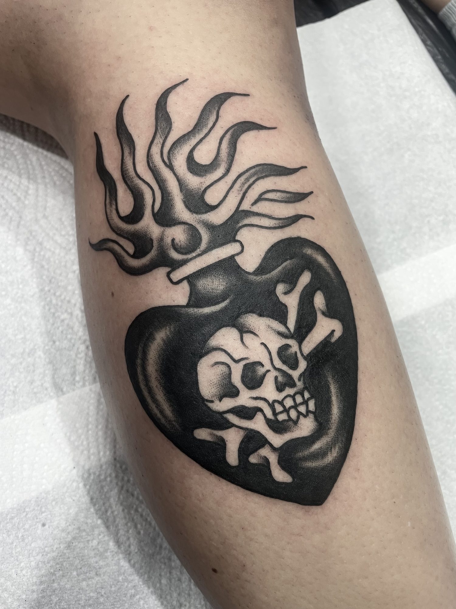 Flammendes Herz mit Totenkopf am Unterarm, Blackwork Tattoo von Jill bei Eine Liebe Tätowiergeschäft in Bochum