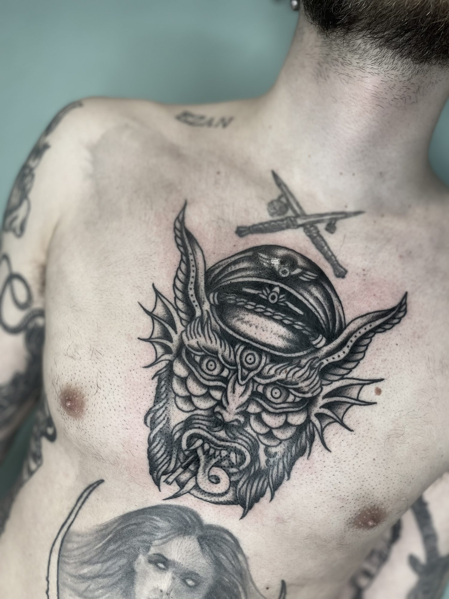 Teufelskopf mit Schirmmütze auf der Brust, Blackwork Tattoo von Jill bei Eine Liebe Tätowiergeschäft in Bochum