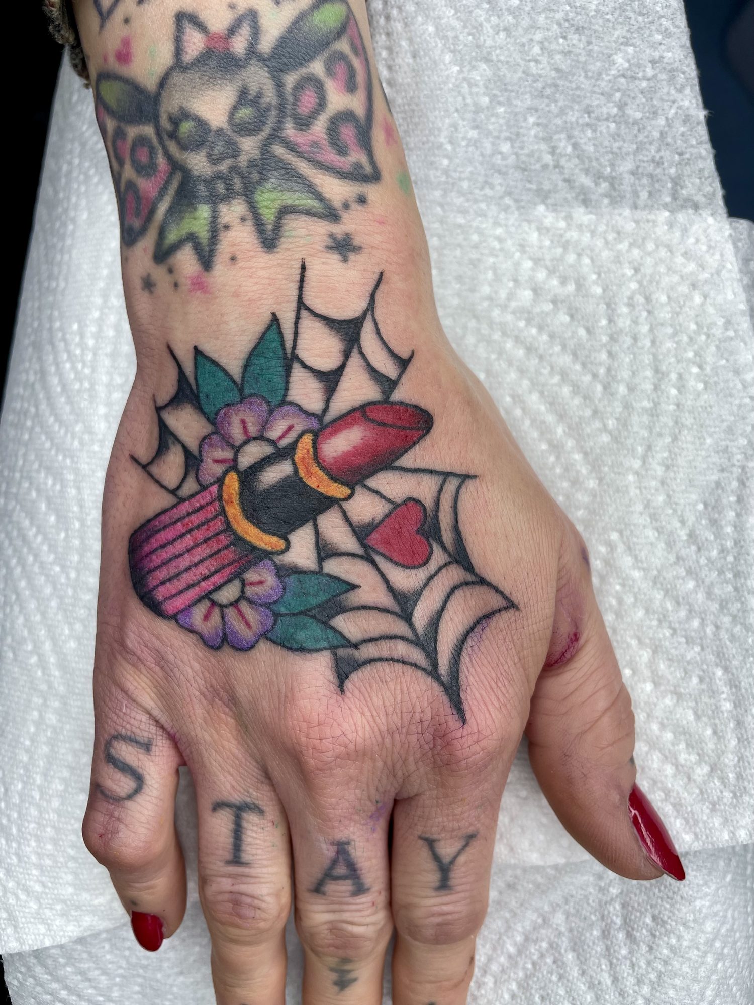 Lippenstift im Spinnennetz auf der Hand, Hand Tattoo von Jill bei Eine Liebe Tätowiergeschäft in Bochum