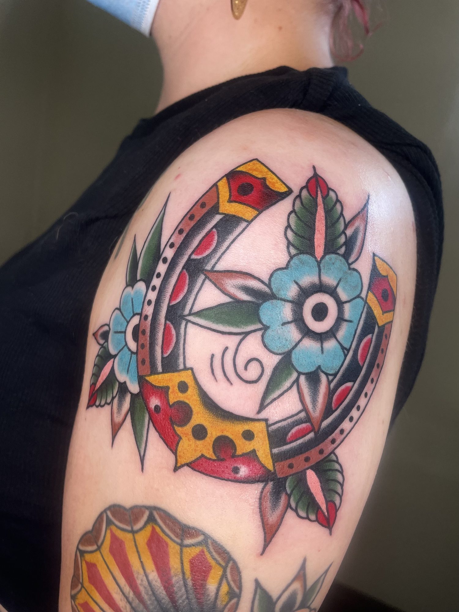 Hufeisen mit Blüten am Oberarm, Traditional Tattoo von Jill bei Eine Liebe Tätowiergeschäft in Bochum