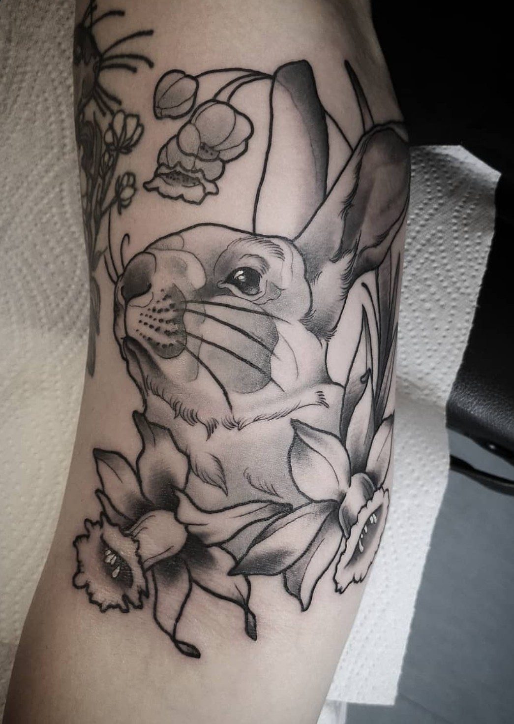 Kaninchen mit Narzissen am Oberarm, Blackwork Tattoo von Melissa bei Eine Liebe Tätowiergeschäft in Bochum